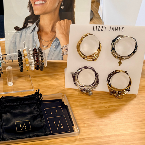 Lizzy James jewelry display with hoop earrings on a wooden table.
