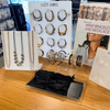 Lizzy James jewelry display with necklaces, bracelets, and packaging on a wooden surface.