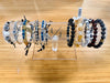 Collection of bracelets on a clear acrylic stand against a wooden background